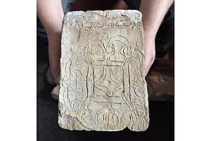 Backstein mit gotischer Ornamentritzung und Inschrift.
