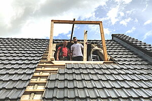 Vorarbeiter Benjamin Gibcke (l.) und Geselle Etienne Schiemann von der Rostocker Firma Luks & Voigt errichteten zu Beginn der Sanierung eine provisorische Gaube im Dach. Darüber erfolgt der Austausch des Dämmmaterials.